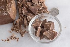 a glass jar filled with chocolate next to a pile of chopped up pieces of chocolate