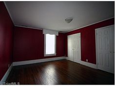 an empty room with red walls and wooden floors