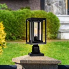 a small black lantern sitting on top of a cement block in front of some grass