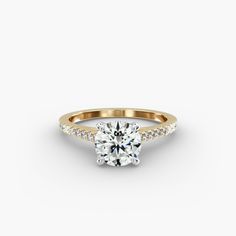 a yellow gold engagement ring with a round brilliant diamond in the center and pave set shoulders