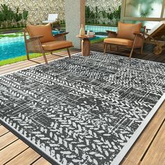 an outdoor area with chairs, table and rug on the deck next to a swimming pool