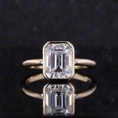 an emerald - cut diamond ring sits on a black surface