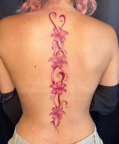 a woman's back tattoo with pink flowers and vines on her lower back,