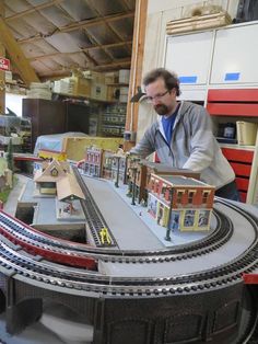 a man standing next to a model train set