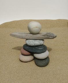 a pile of rocks sitting on top of a sandy beach next to a wooden stick