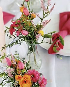 two vases filled with flowers sitting on top of a white tablecloth covered table