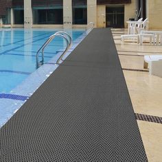 an empty swimming pool with chairs and tables in the backround, next to it