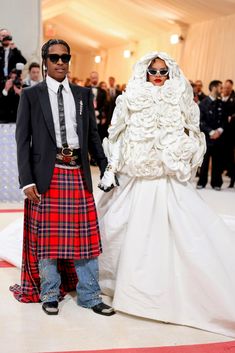 a man and woman dressed in kilts standing next to each other at a formal event