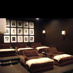 an empty theater room with brown couches and pictures on the wall behind them,