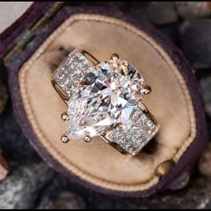 a cushion cut diamond ring sitting on top of a leather case