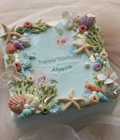 a birthday cake decorated with seashells and starfish on top of a bed