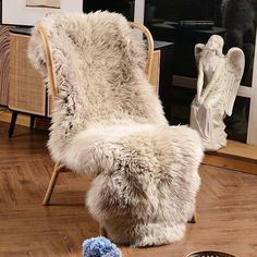 a white chair sitting on top of a hard wood floor next to a blue pom pom