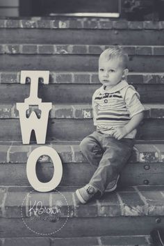 a little boy sitting on some stairs with the word two spelled in front of him