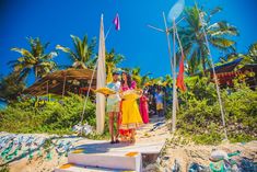 two women standing on the beach with flags in front of them and people behind them