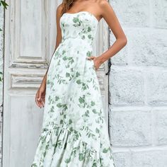 a woman standing in front of a door wearing a white dress with green flowers on it