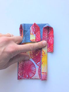 a hand is pointing at a folded piece of fabric with fireworks on it and the other half has a finger