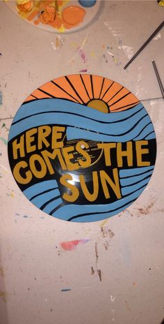 there is a sticker that says here comes the sun on top of a table