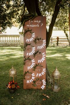 a wooden sign sitting on top of a lush green field next to a lamp post