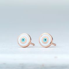 Handmade solid gold evil eye earrings, round shaped.  White evil eye set in 14k solid gold. Available in yellow, white or rose solid gold. The evil eye studs measure  7mm and have 14k solid gold posts and ear nuts. Simple eye catching minimal earrings great for everyday wear.  PLEASE NOTE THAT DHL EXPRESS SHIPPING MIGHT BE MORE EXPENSIVE OR NOT POSSIBLE FOR SOME REMOTE OR DANGEROUS AREAS Gift White Earrings With Diamond Eyes, Nickel-free 14k Gold White Earrings, Nickel-free White 14k Gold Earrings, White 14k Gold Nickel-free Earrings, White Evil Eye, Second Hole Earrings, Gold Jewelry Gift, Simple Eye, White Gold Studs