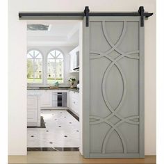 an open door leading to a kitchen with white cabinets and black hardware on the doors