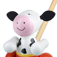 a toy cow with a wooden stick in its mouth sitting on top of a ball