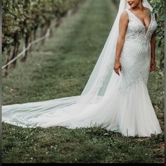 a woman wearing a wedding dress standing in an apple orchard