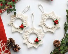 three christmas wreaths made out of yarn and pine cones