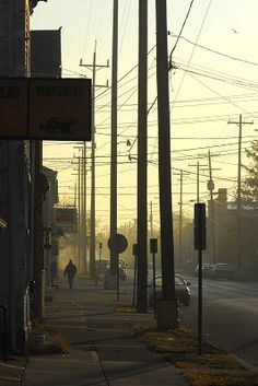 a person walking down the sidewalk in front of a building with power lines above it