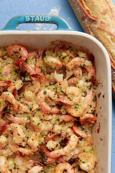 a casserole dish with shrimp and bread on the side, ready to be eaten