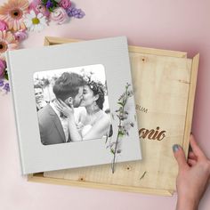 a wooden box with a photo and flowers on the inside is holding a wedding album