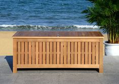 a large wooden box sitting on top of a sidewalk next to the ocean and palm trees