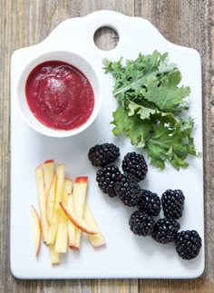 an assortment of fruits and vegetables are arranged on a white plate, including apples, blackberries, and beets