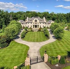 an aerial view of a large home surrounded by lush green grass and trees in the foreground