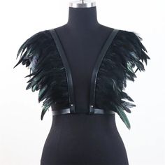 a mannequin with black feathers on it's chest and back, in front of a white background