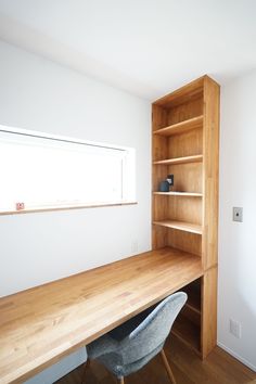 an empty room with a desk and bookcase in the corner, next to a window