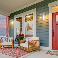 two wooden chairs sitting on top of a rug next to a red door and window