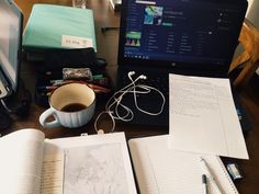 an open laptop computer sitting on top of a desk next to a cup of coffee