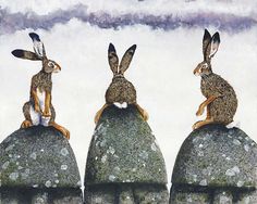 three rabbits sitting on top of rocks with clouds in the background and one rabbit standing up