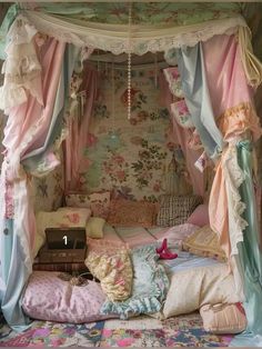 a canopy bed with pink and blue drapes on the top, pillows in the bottom