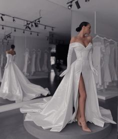 a woman standing in front of a mirror wearing a white dress and high slit skirt