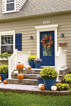 the front porch is decorated with pumpkins and flowers