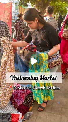 a woman standing next to a pile of clothes on top of a sidewalk with the words wednesday market st michael church, miami