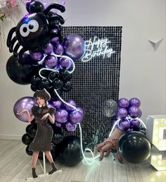 a woman standing in front of balloons with a spider on it