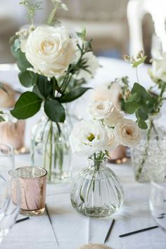 several vases filled with white flowers on top of a table