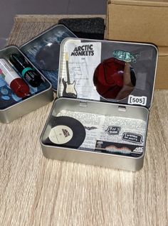 two tins with various items in them sitting on a table