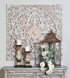 a table with two vases on top of it and a wall hanging behind it