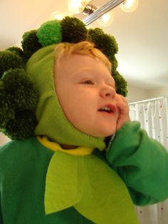 a child wearing a green frog costume and holding his hand to his face while standing in front of a mirror