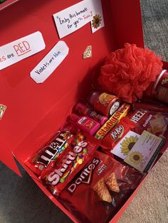 a red box filled with lots of candy and candies on top of carpeted floor