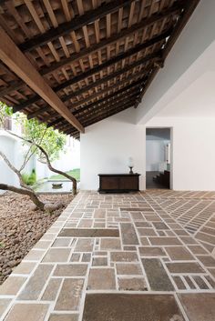 the interior of a house with stone flooring and wooden roof over looking a garden