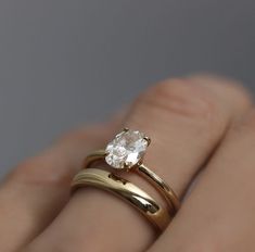 a close up of a person's hand holding a ring with a diamond on it